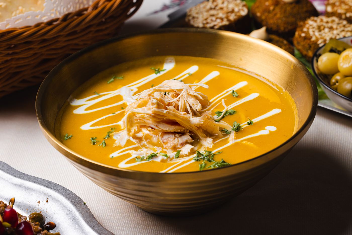 Soup Adas: Persian lentil soup with shredded chicken, cream and fresh herbs in a brass bowl