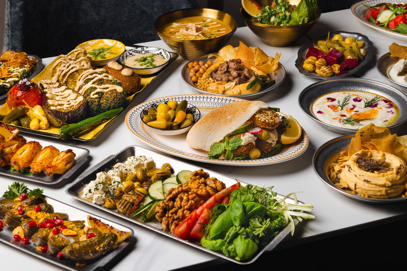 A mezze spread at Shirazi: dolma, falafel pita pocket, hummus, pickles and fresh herbs across the table