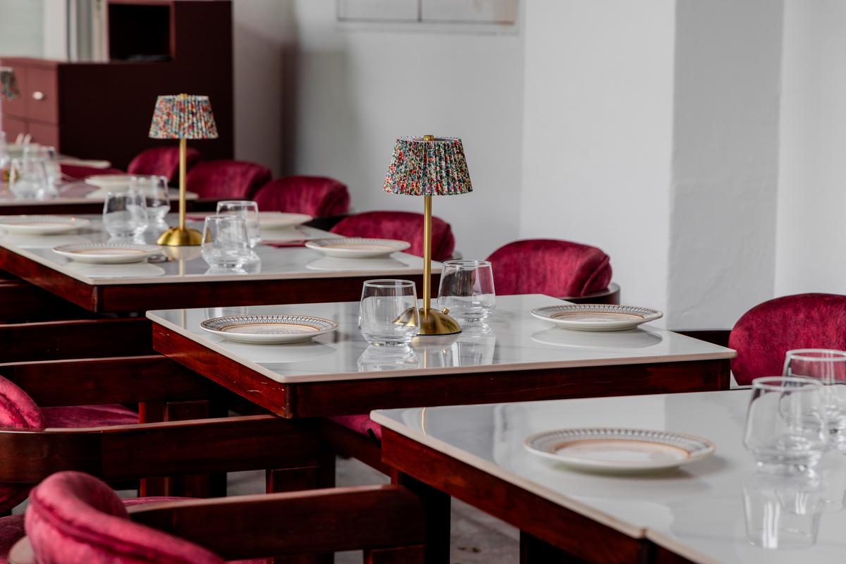 Window tables with burgundy velvet chairs and beaded lamps