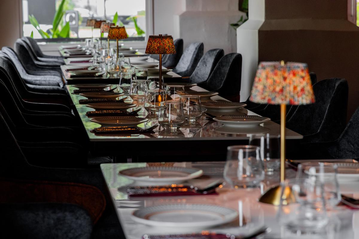 The long table, laid and waiting under its row of lamps