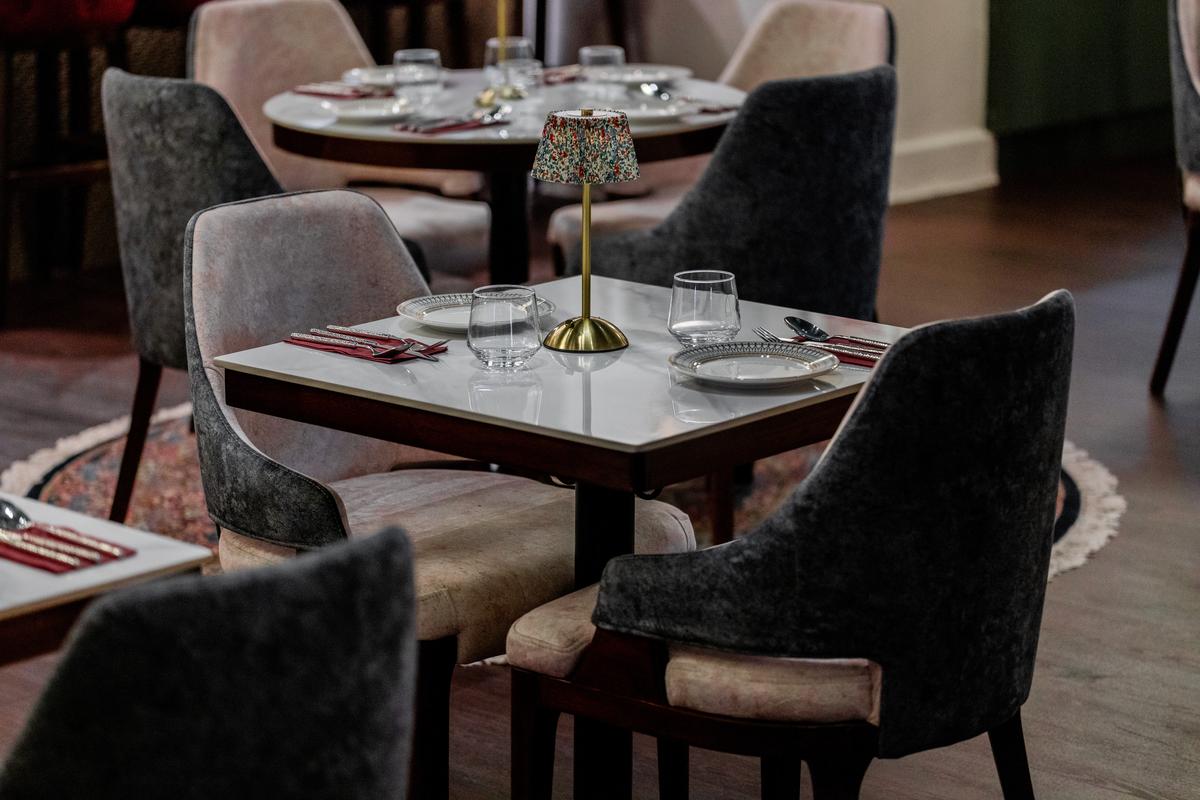 A corner table for four, velvet armchairs drawn close